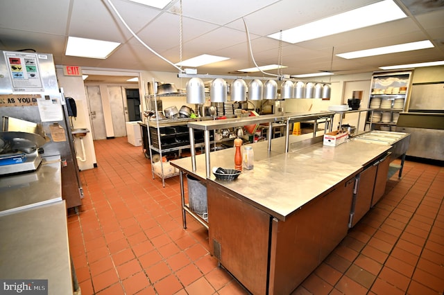 kitchen featuring a paneled ceiling, a center island, and tile floors