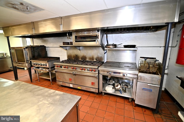 kitchen featuring dark tile floors, tasteful backsplash, stainless steel counters, and double oven range