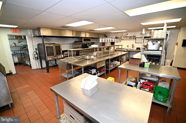 kitchen with dark tile flooring, a paneled ceiling, and stainless steel counters