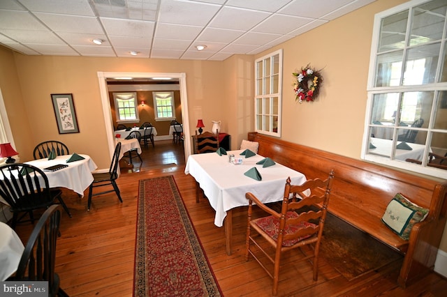 dining area with wood-type flooring and a drop ceiling