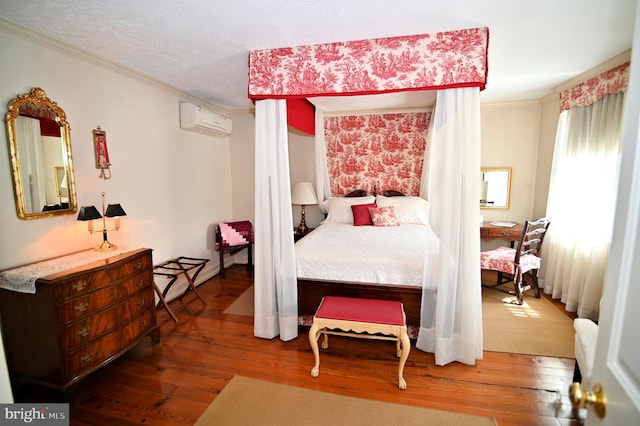 bedroom with a textured ceiling, hardwood / wood-style flooring, and a wall unit AC