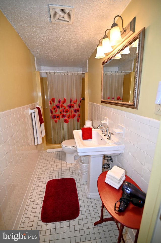 bathroom featuring toilet, tile walls, tile flooring, and tasteful backsplash