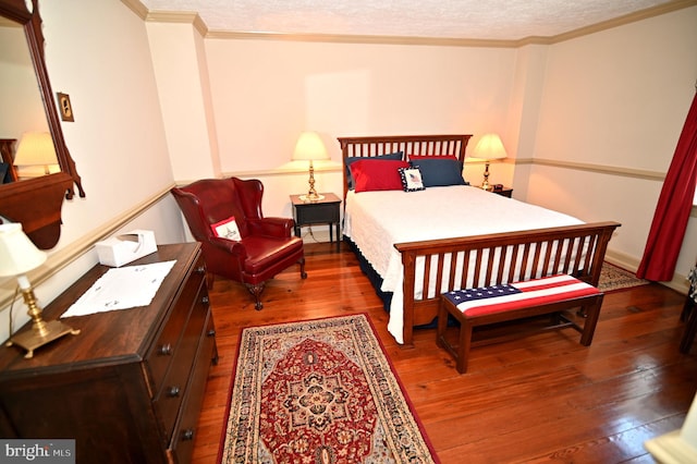 bedroom featuring dark hardwood / wood-style flooring, a textured ceiling, and ornamental molding