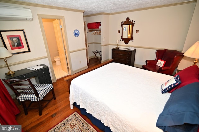 bedroom featuring a wall unit AC, dark hardwood / wood-style floors, connected bathroom, a textured ceiling, and a closet