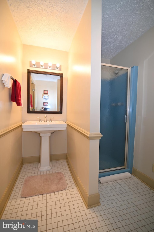 bathroom featuring tile flooring, walk in shower, and a textured ceiling