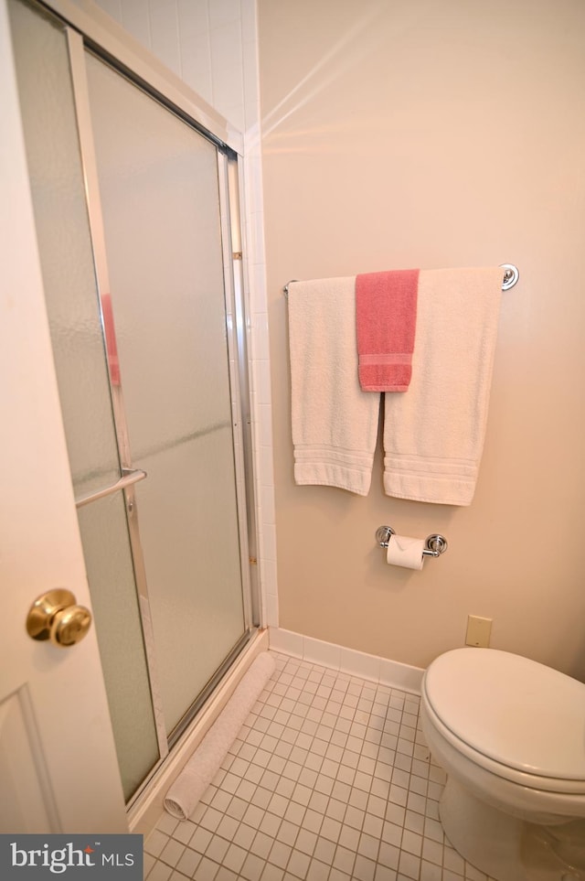 bathroom with toilet, tile flooring, and an enclosed shower