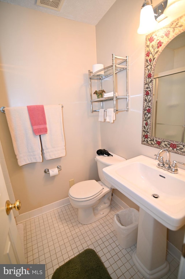 bathroom featuring toilet, a textured ceiling, and tile flooring