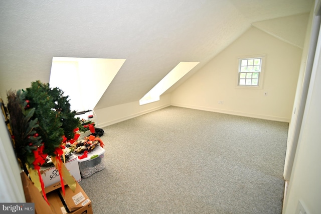 bonus room featuring vaulted ceiling with skylight, a textured ceiling, and carpet