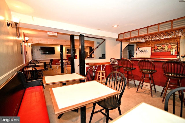 dining area with bar area and light carpet