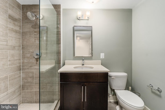 bathroom featuring a shower with door, toilet, and vanity