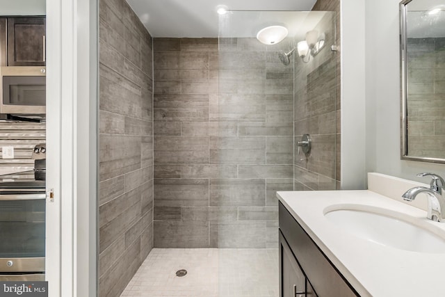 bathroom with tiled shower and vanity with extensive cabinet space