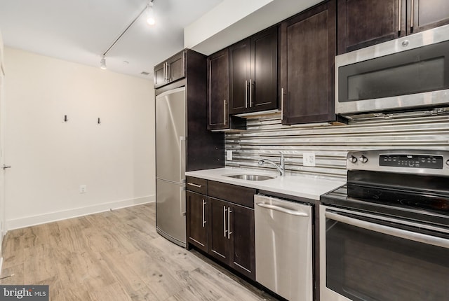 kitchen featuring backsplash, appliances with stainless steel finishes, track lighting, light hardwood / wood-style floors, and dark brown cabinets