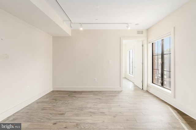 empty room featuring track lighting and light hardwood / wood-style floors