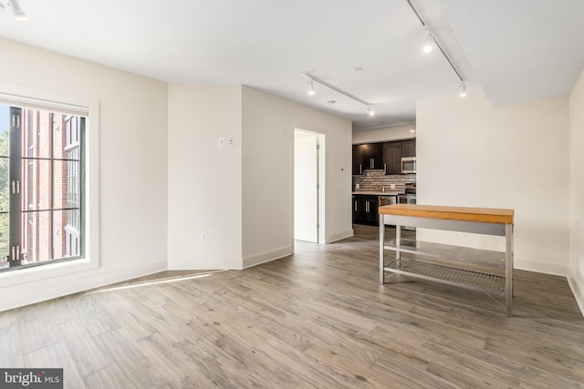 spare room featuring wood-type flooring, a healthy amount of sunlight, and rail lighting