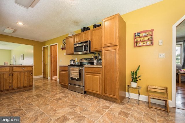 kitchen featuring light tile floors, appliances with stainless steel finishes, and a textured ceiling