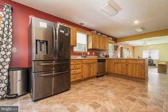 kitchen with appliances with stainless steel finishes, ceiling fan, a textured ceiling, sink, and light tile flooring