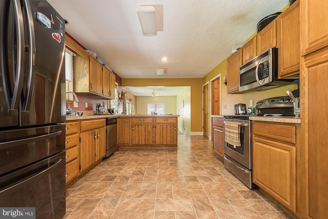 kitchen with light tile flooring, sink, stainless steel appliances, and a textured ceiling