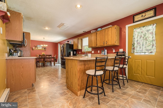 kitchen featuring a chandelier, decorative light fixtures, a baseboard heating unit, kitchen peninsula, and a breakfast bar area