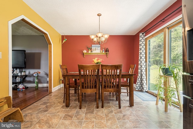 dining room featuring a notable chandelier, a textured ceiling, and light tile flooring