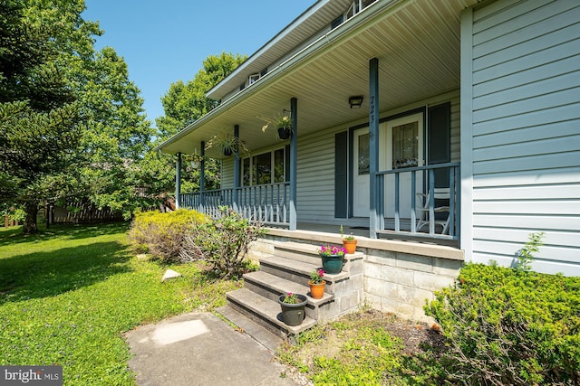 doorway to property with covered porch and a yard