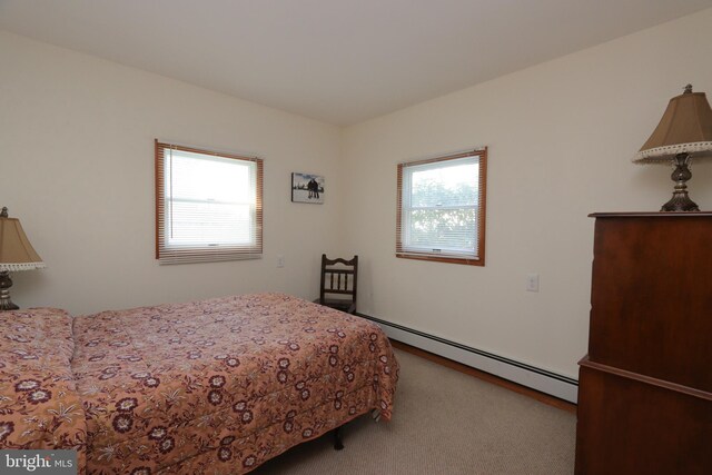 carpeted bedroom featuring multiple windows and baseboard heating