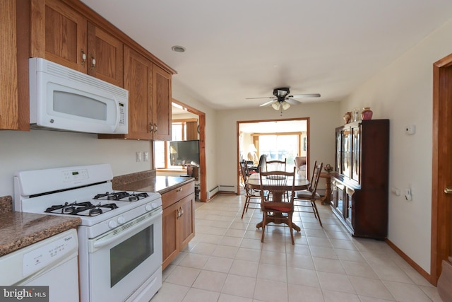 kitchen with light tile flooring, ceiling fan, white appliances, and dark stone countertops