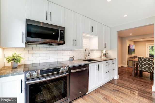 10905 Harpers Square Ct, Reston, VA 20191 - kitchen featuring a sink, stone counters, light wood-style flooring, white cabinetry, and appliances with stainless steel finishes
