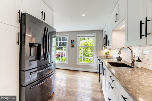 10905 Harpers Square Ct, Reston, VA 20191 - kitchen featuring light stone countertops, stainless steel appliances, a sink, baseboards, and light wood-type flooring