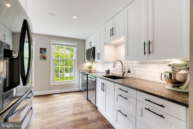 10905 Harpers Square Ct, Reston, VA 20191 - kitchen with dark stone countertops, a sink, light wood-style floors, stainless steel appliances, and baseboards