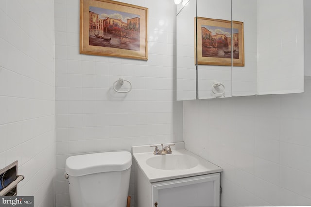 bathroom featuring vanity, toilet, and tile walls