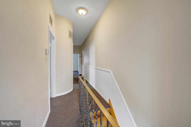 hall with dark colored carpet