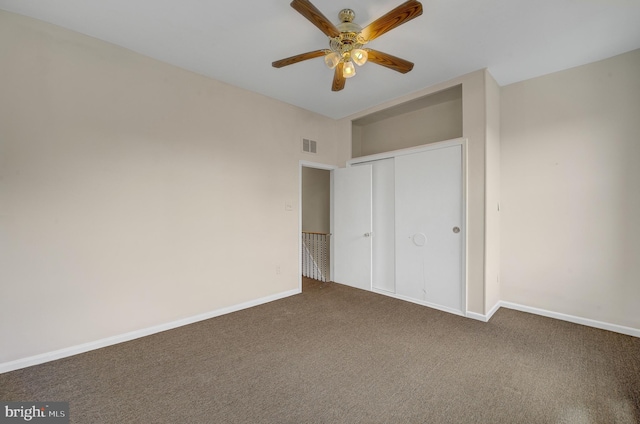 unfurnished bedroom with ceiling fan, dark colored carpet, and a closet