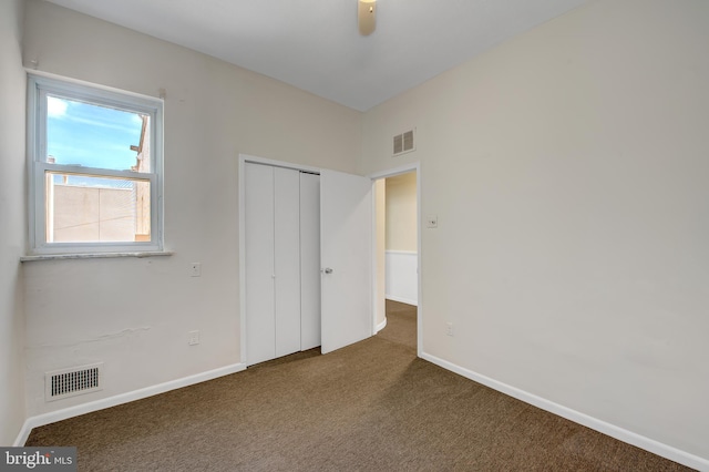 unfurnished bedroom featuring a closet and dark colored carpet