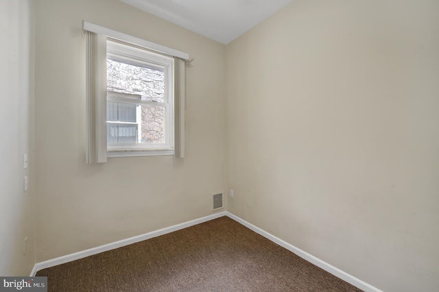 spare room featuring dark carpet