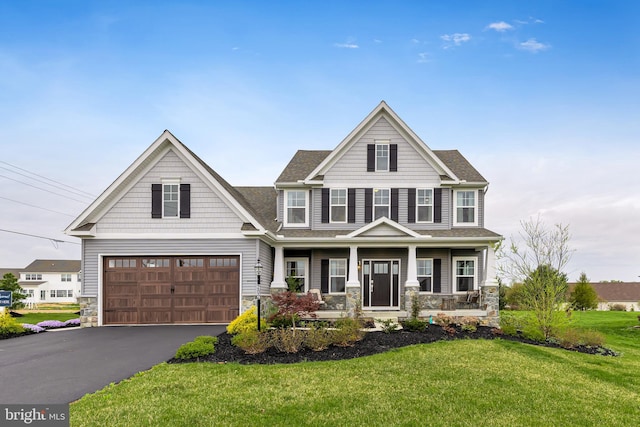 view of front of house featuring covered porch, a front yard, and a garage