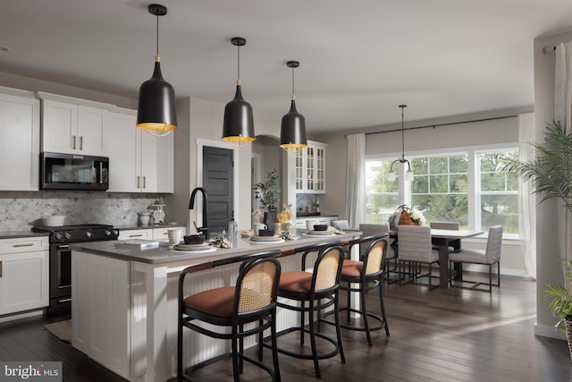 kitchen featuring white cabinetry, electric range, hanging light fixtures, tasteful backsplash, and an island with sink