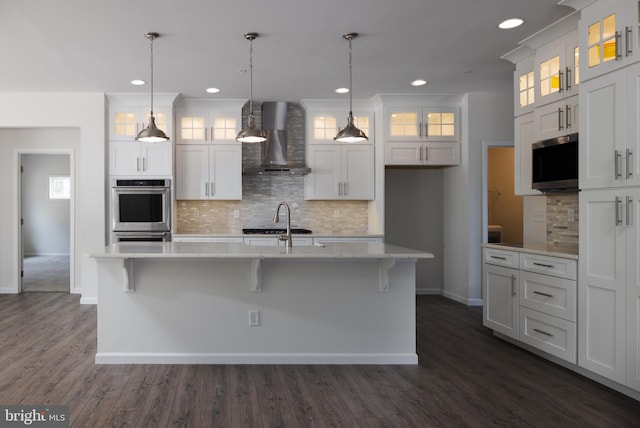 kitchen with white cabinets, a center island with sink, and wall chimney exhaust hood