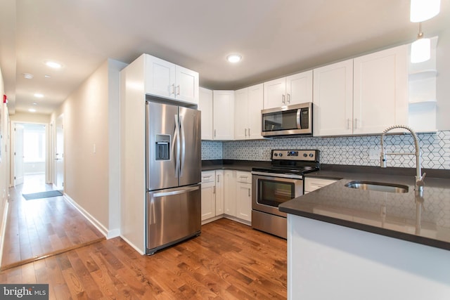 kitchen featuring tasteful backsplash, stainless steel appliances, sink, white cabinetry, and dark hardwood / wood-style floors