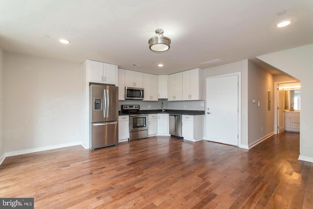 kitchen with sink, white cabinetry, appliances with stainless steel finishes, and wood-type flooring