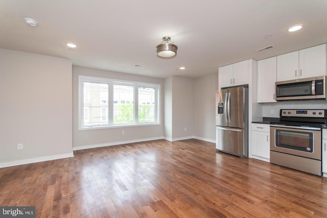 kitchen featuring stainless steel appliances, tasteful backsplash, dark wood-type flooring, and white cabinetry