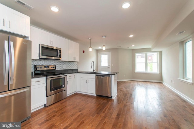 kitchen with decorative light fixtures, white cabinets, dark hardwood / wood-style floors, stainless steel appliances, and backsplash