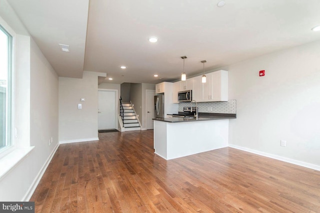 kitchen featuring white cabinetry, kitchen peninsula, appliances with stainless steel finishes, and hardwood / wood-style flooring