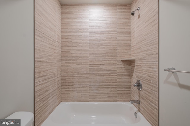 bathroom featuring tiled shower / bath combo and toilet