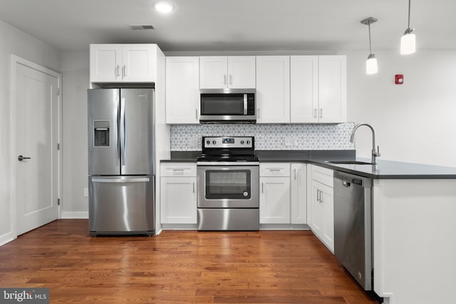 kitchen with dark hardwood / wood-style flooring, decorative light fixtures, appliances with stainless steel finishes, and white cabinets