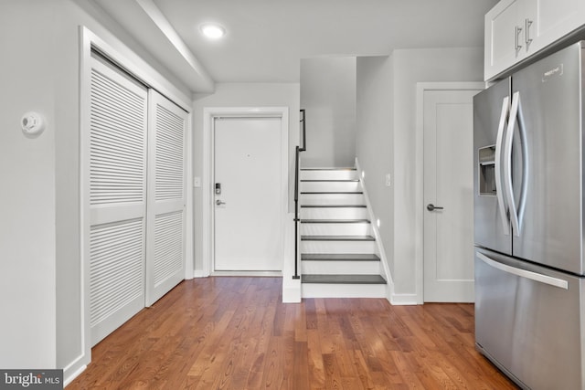 interior space featuring white cabinets, hardwood / wood-style flooring, and stainless steel fridge