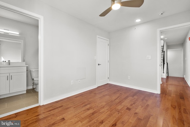 interior space featuring ceiling fan, ensuite bath, and wood-type flooring