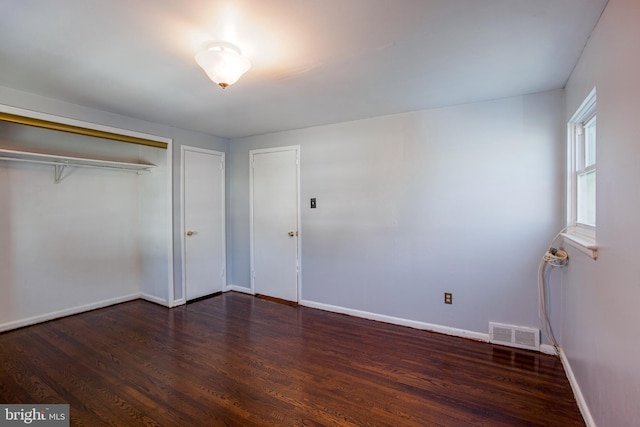 unfurnished bedroom featuring dark hardwood / wood-style floors and a closet