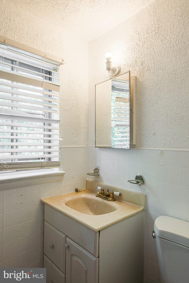 bathroom with a healthy amount of sunlight, oversized vanity, and tile walls