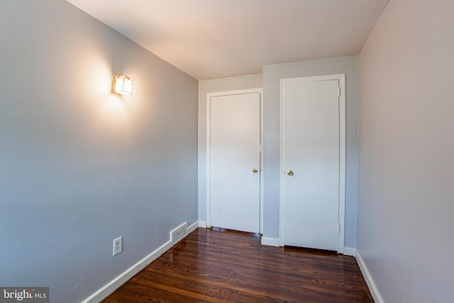 unfurnished bedroom with dark hardwood / wood-style flooring