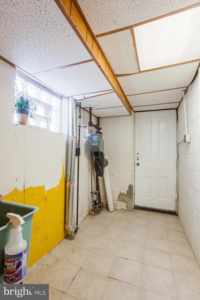 basement featuring light tile flooring and a paneled ceiling